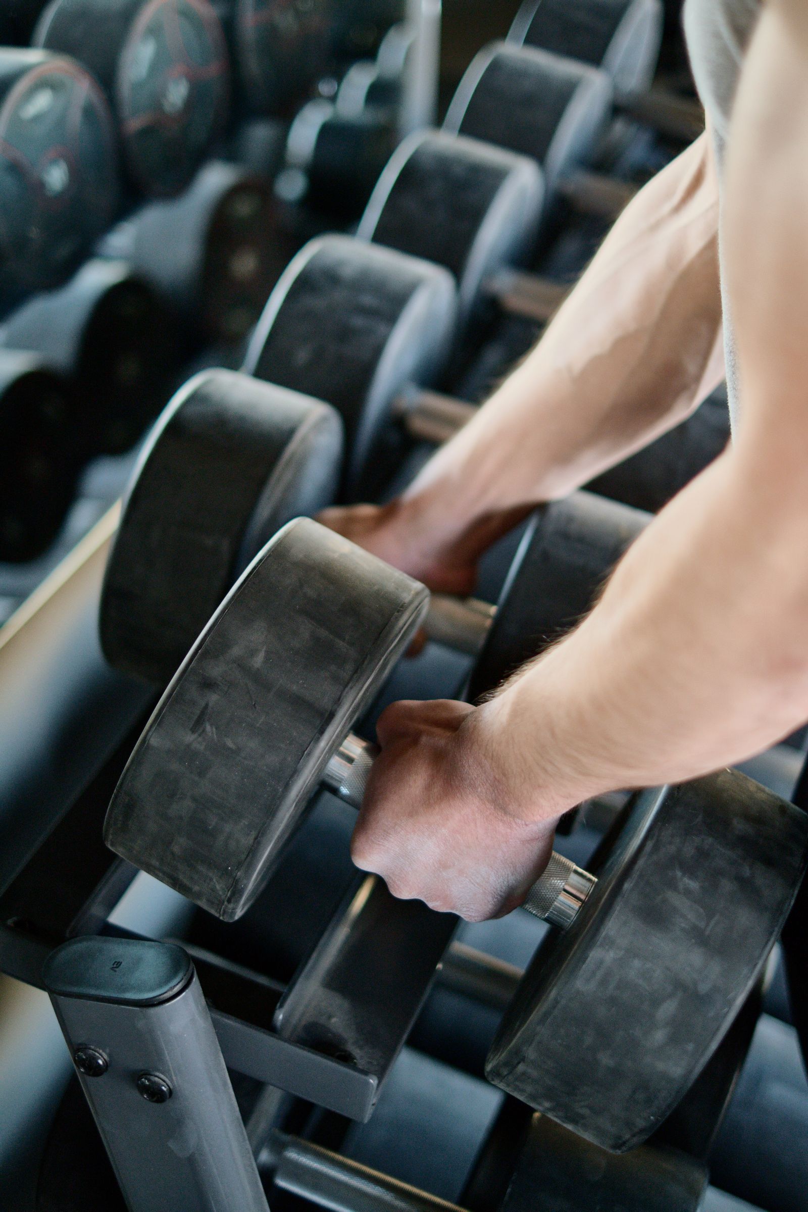 Hands taking dumbbells from rack